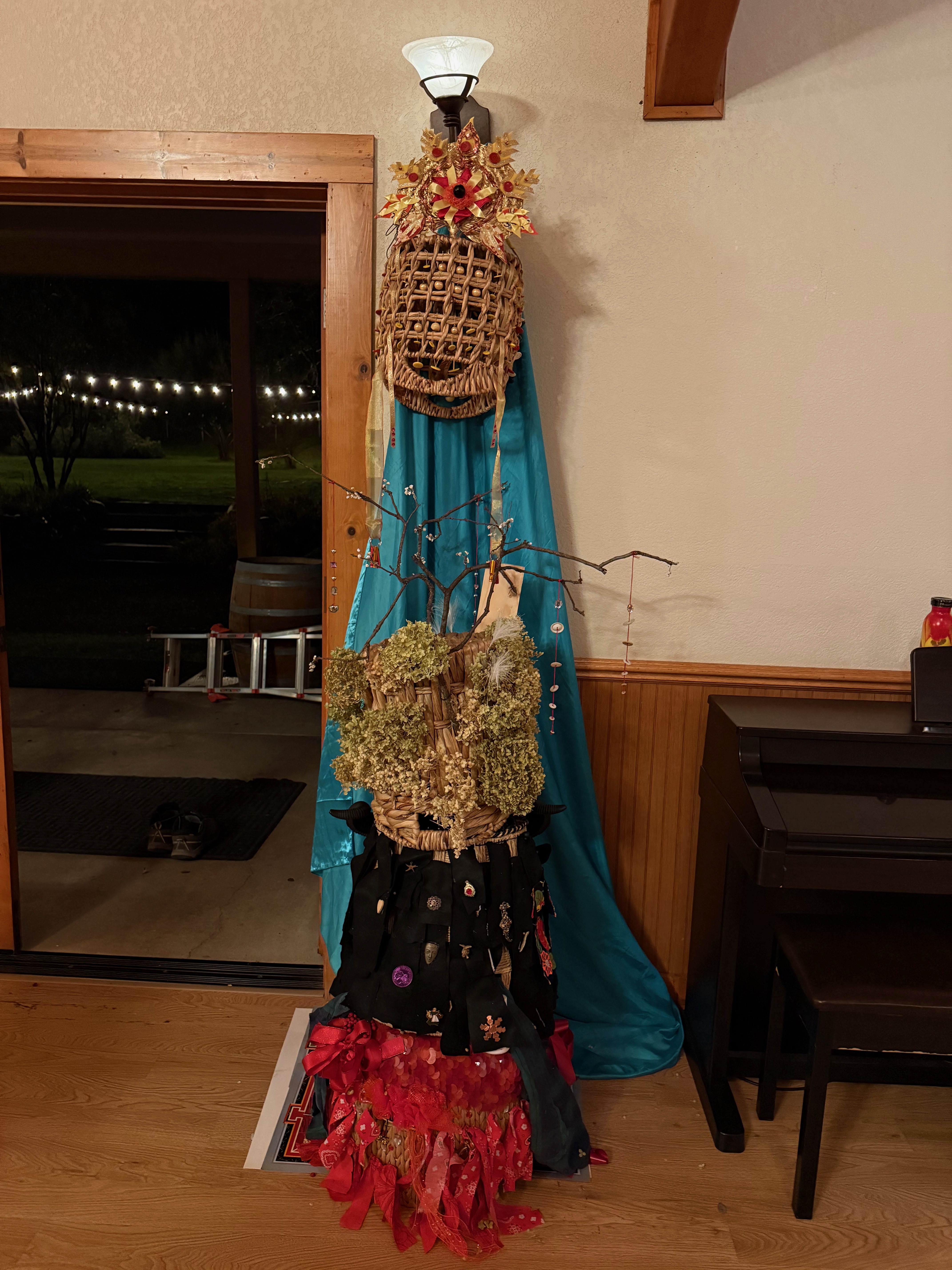 Three headdressess, child, adolescent, and adult, stacked with the spirit headdress suspended above them to form a totem.